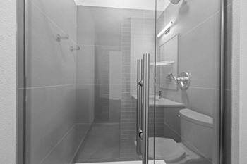 A bathroom with a toilet, sink, and shower at The Avenue Lofts Golden Apartments, Golden, Colorado